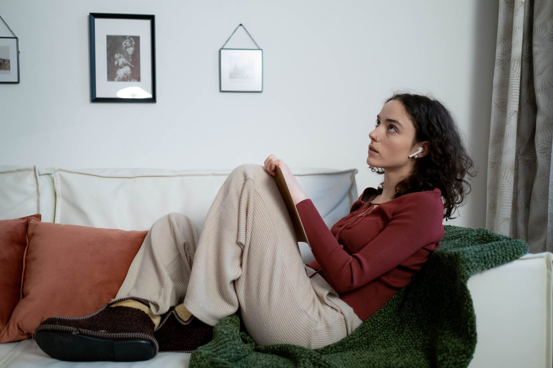a woman resting on a couch holding a notebook while in deep thought