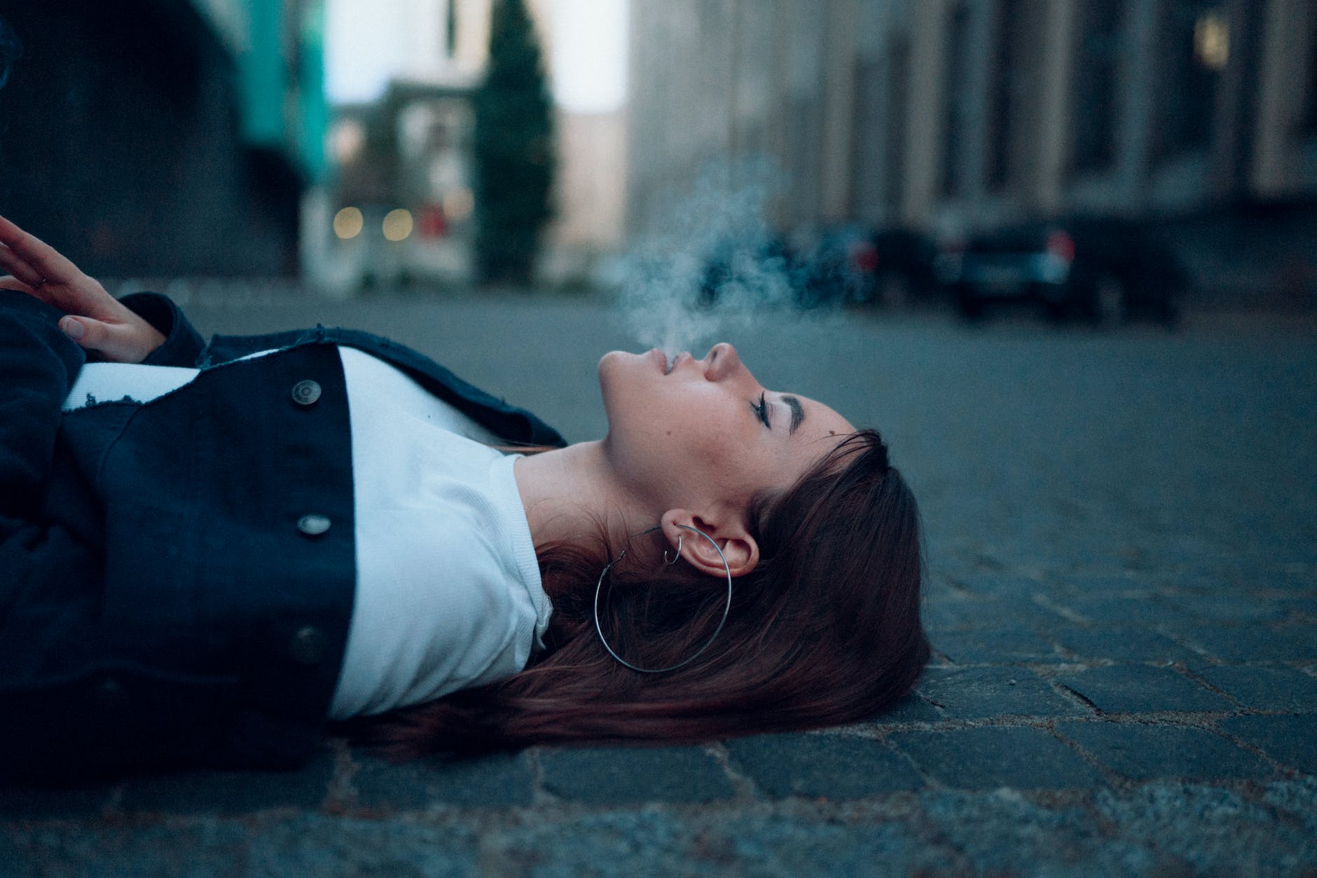 a woman smoking while lying on the road