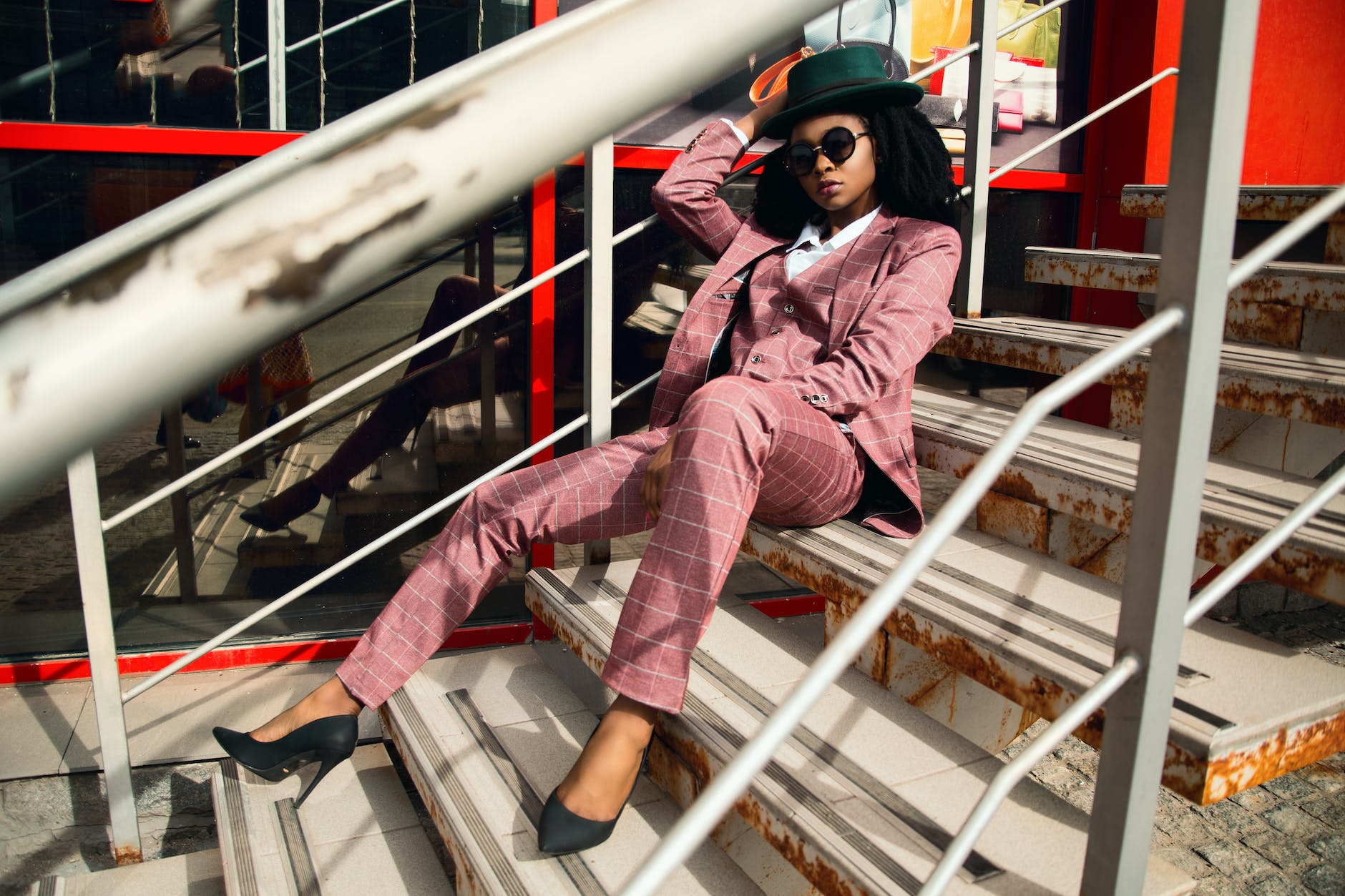 woman wearing pink suit jacket and pants sitting on staircase on graduation